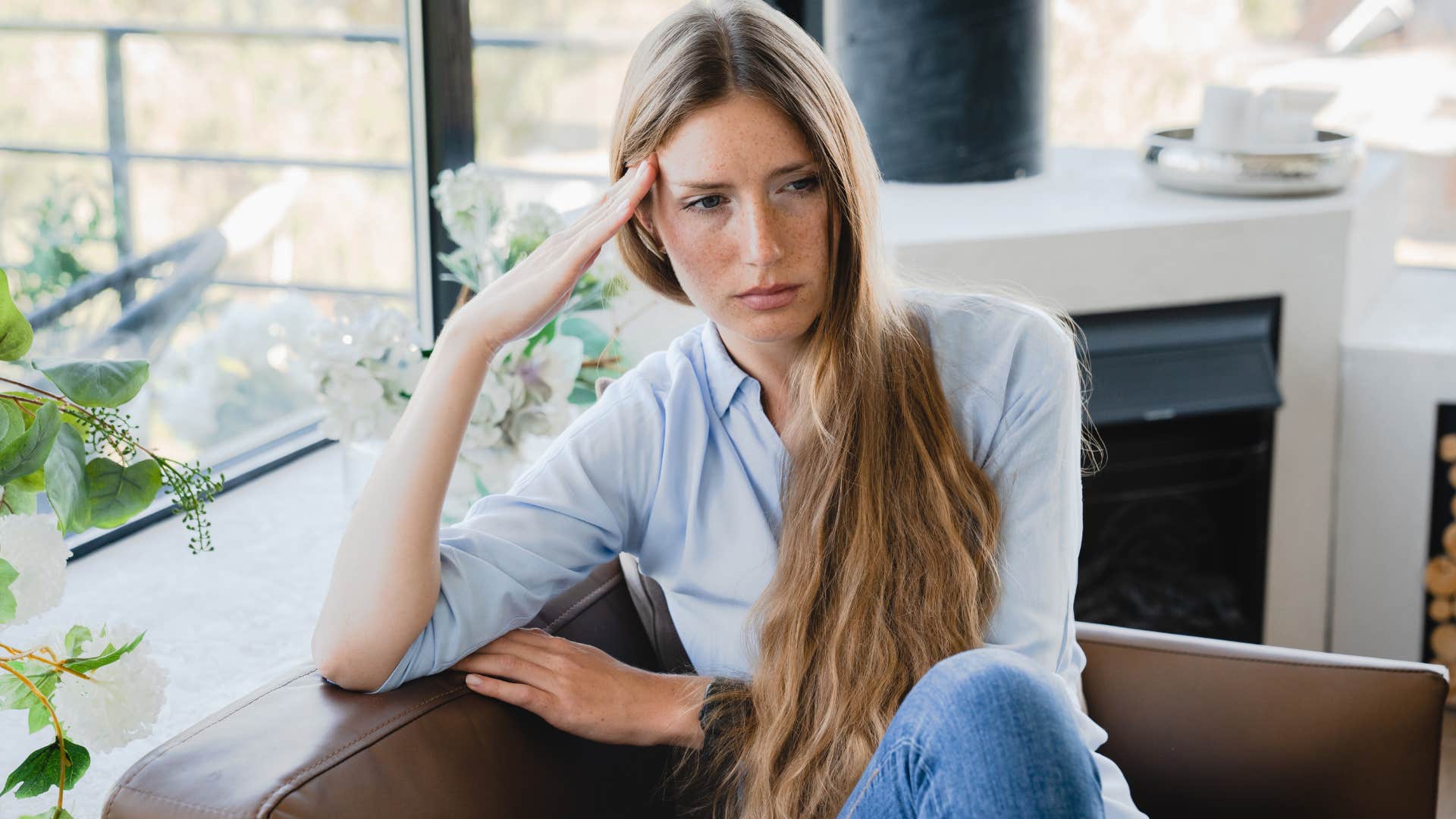 Nervous woman sitting on her couch at home.