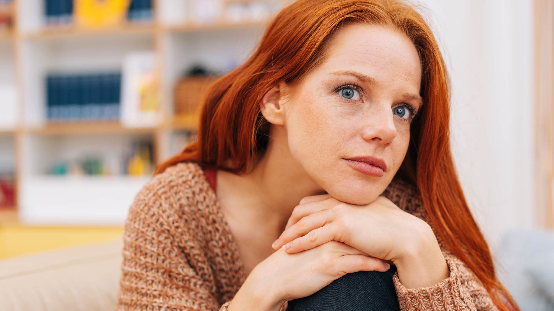 Confident red-haired woman sitting at home.