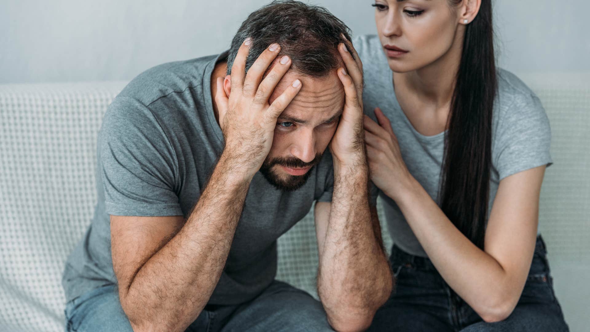 Man looking upset with his head in his hands.