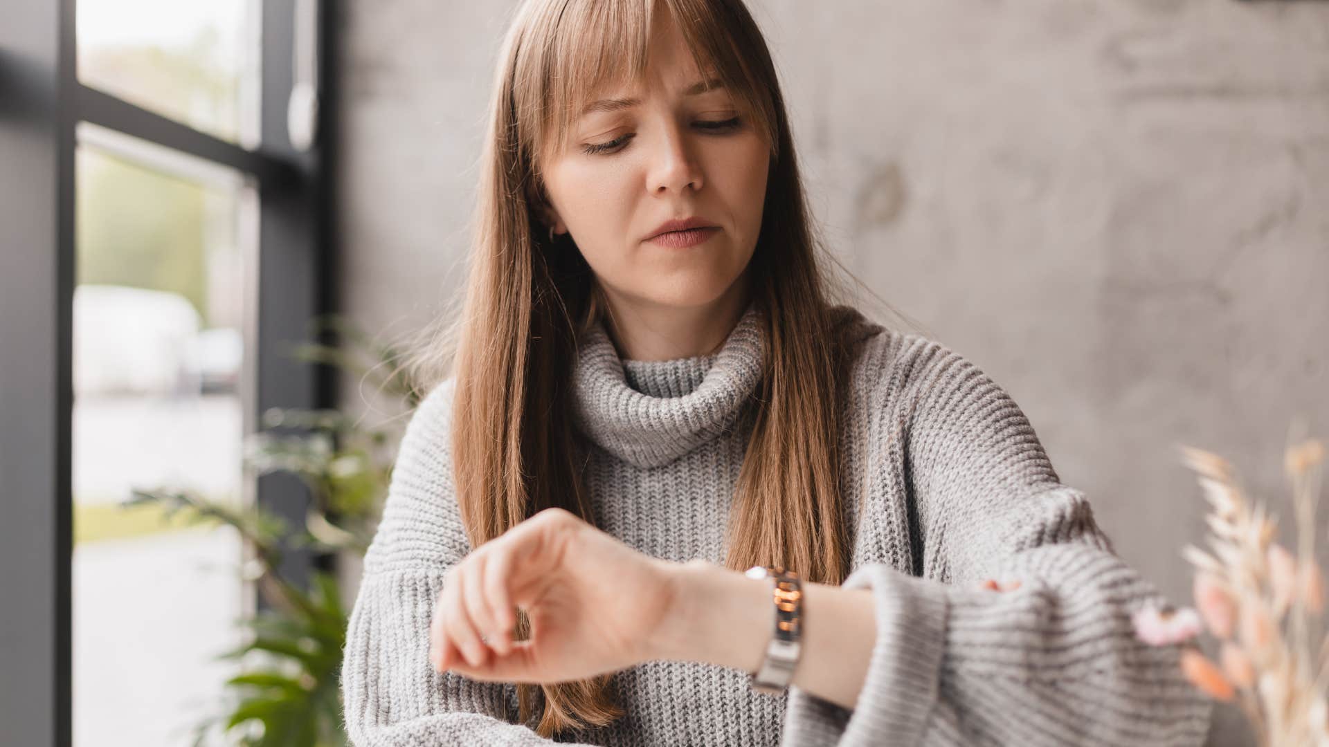 Woman looking seriously down at her watch.