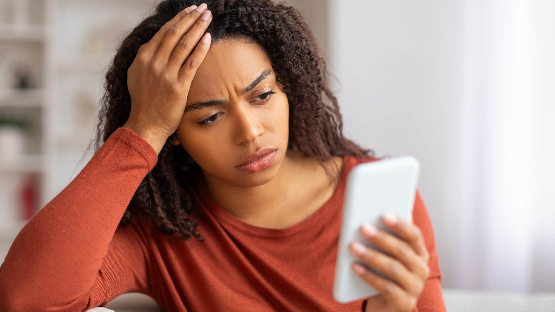 Woman looking confused while staring at her phone. 