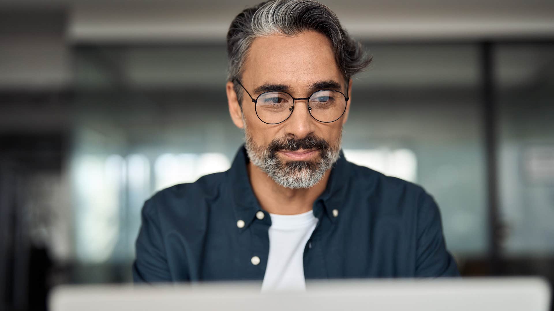 Man calmly looking at his laptop at work.