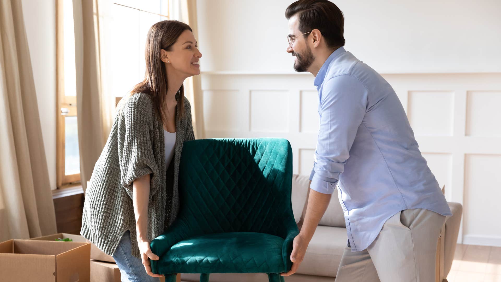 Couple moving a chair around in their apartment.