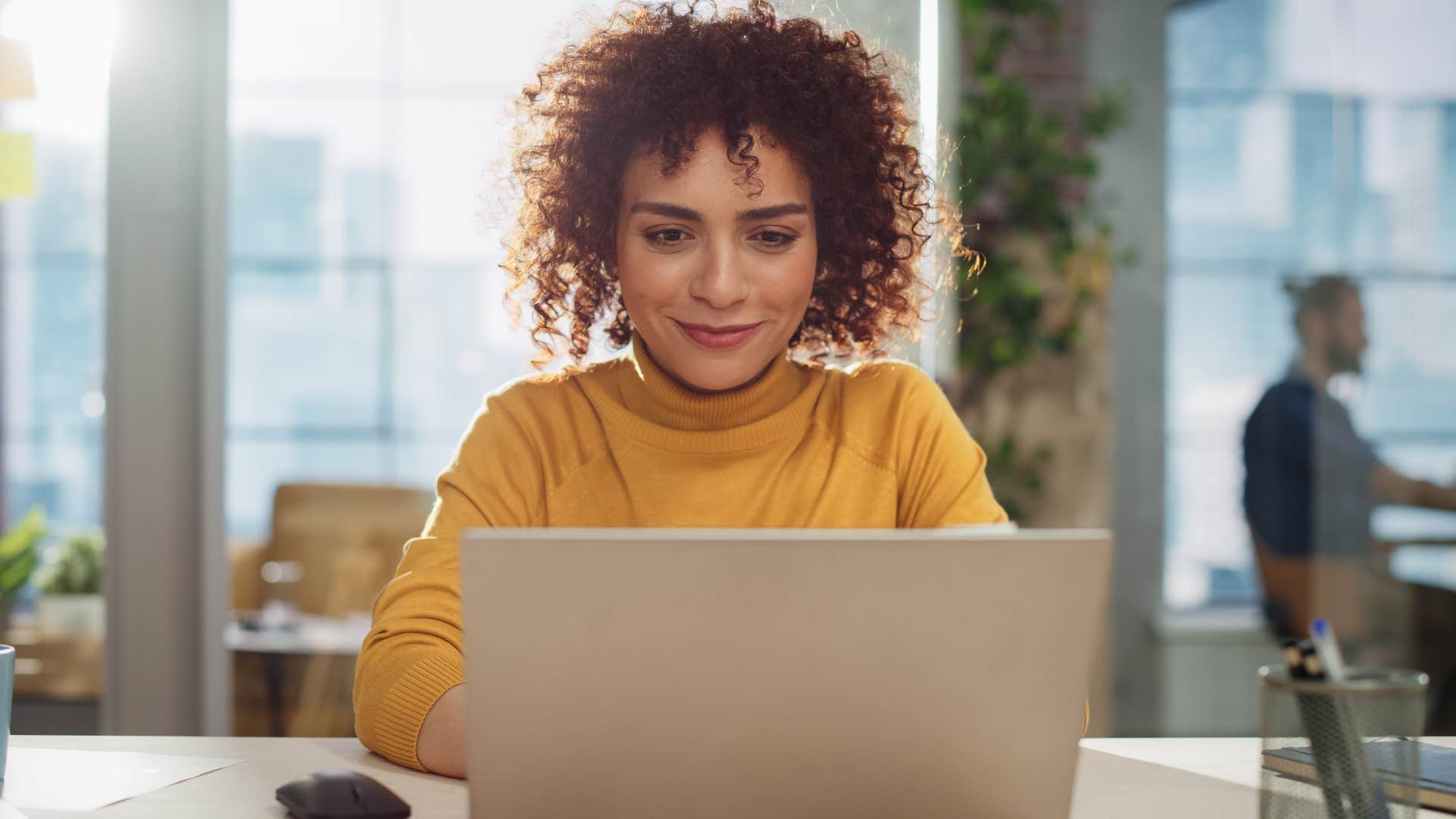 Woman smiling while typing on her laptop.