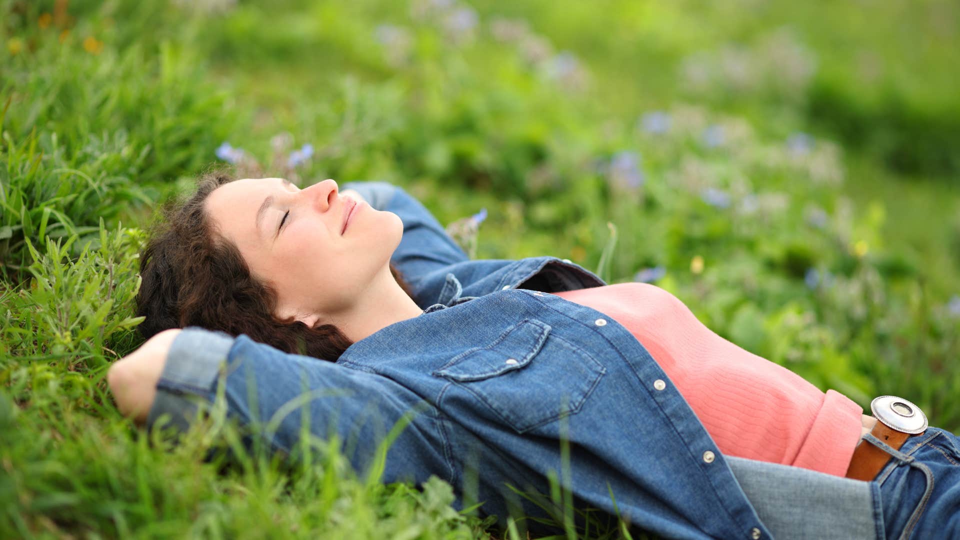 empathic woman laying in grass connecting with nature