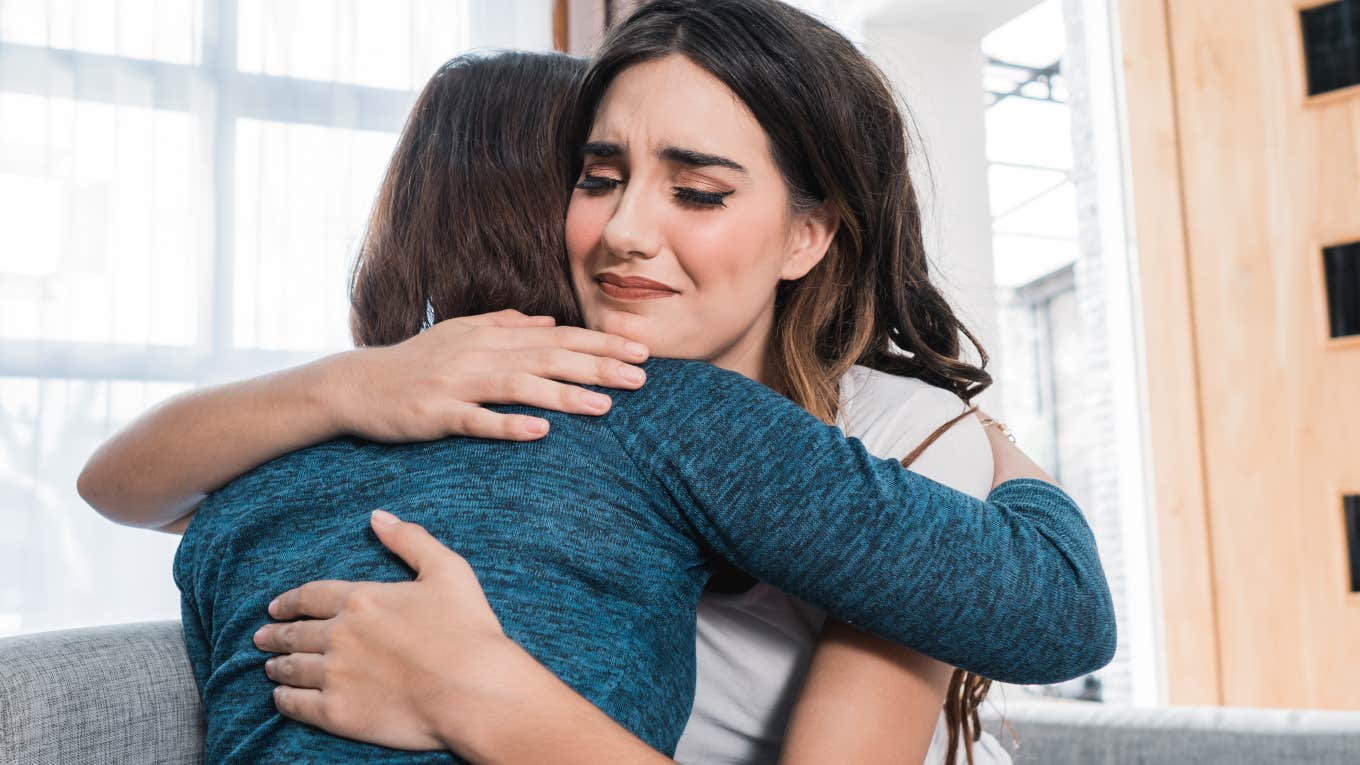 two women hugging while one looks sympathetic