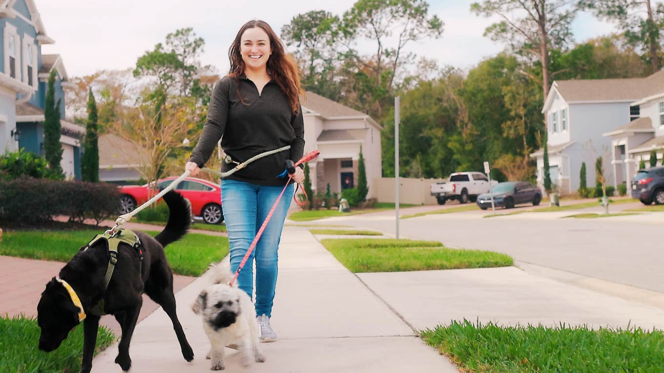 Woman taking care of her mental health, walking dog in neighborhood.