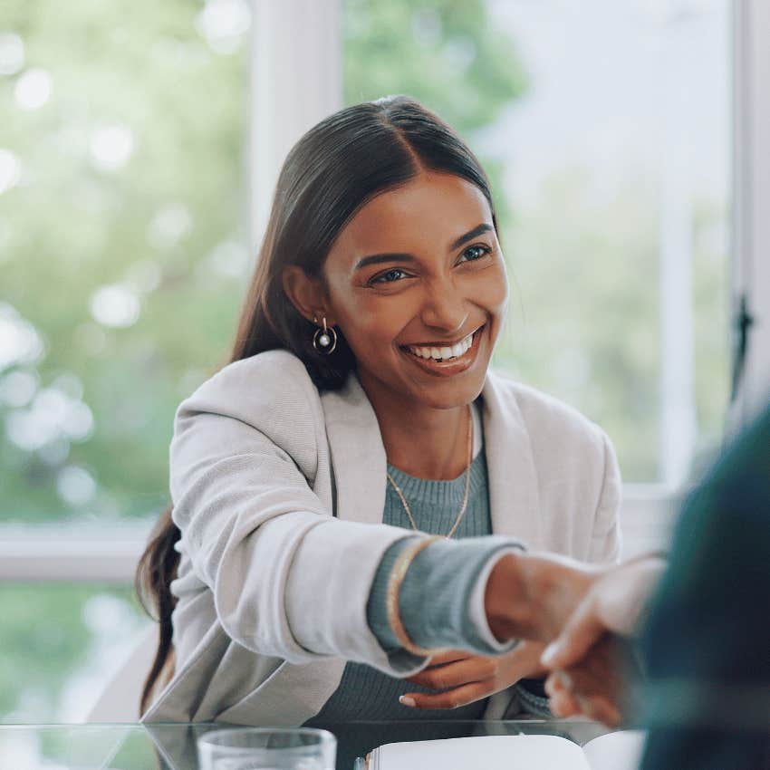 smiling professional woman shaking a persons hand