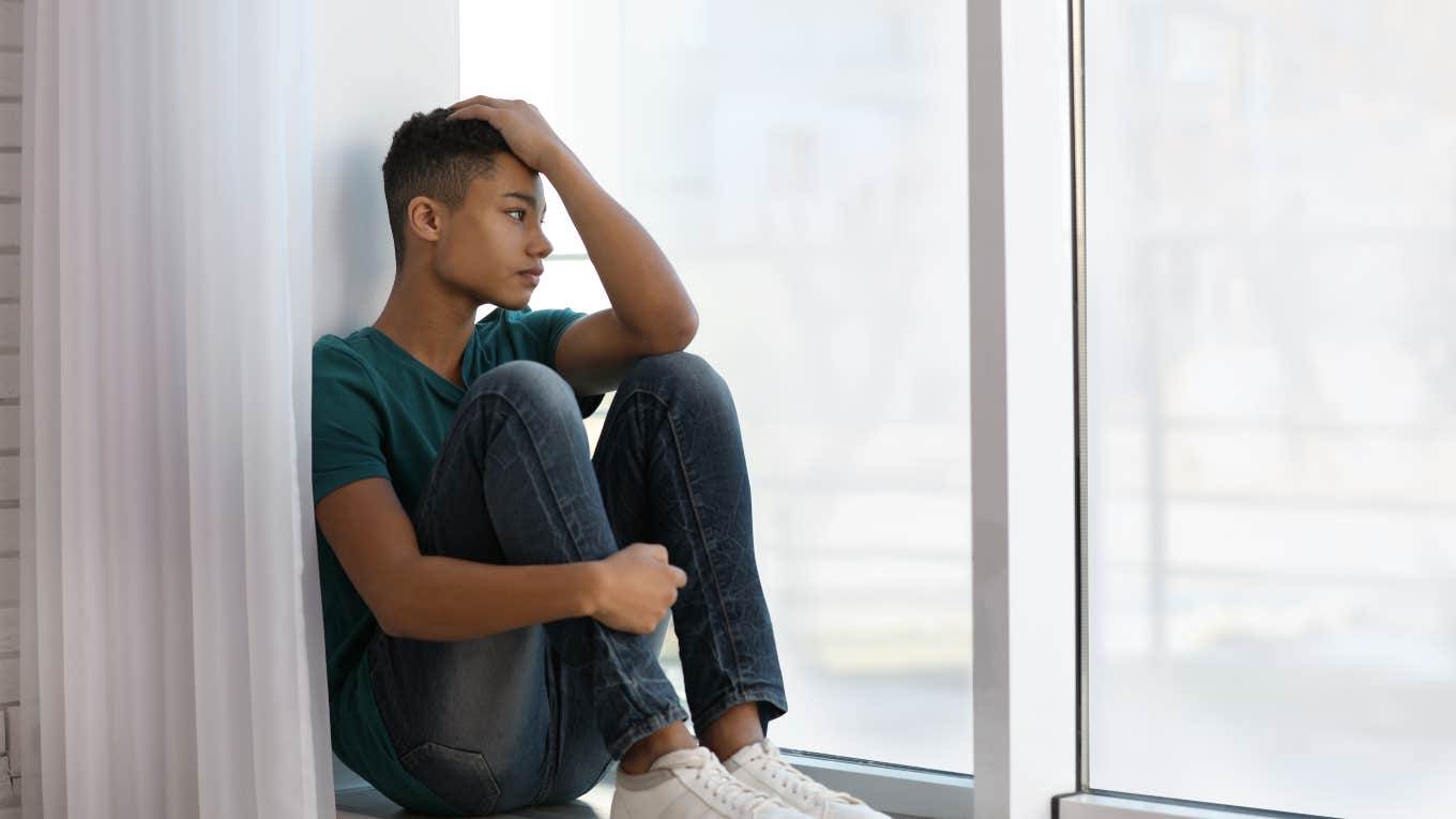 upset teenage boy looking out the window