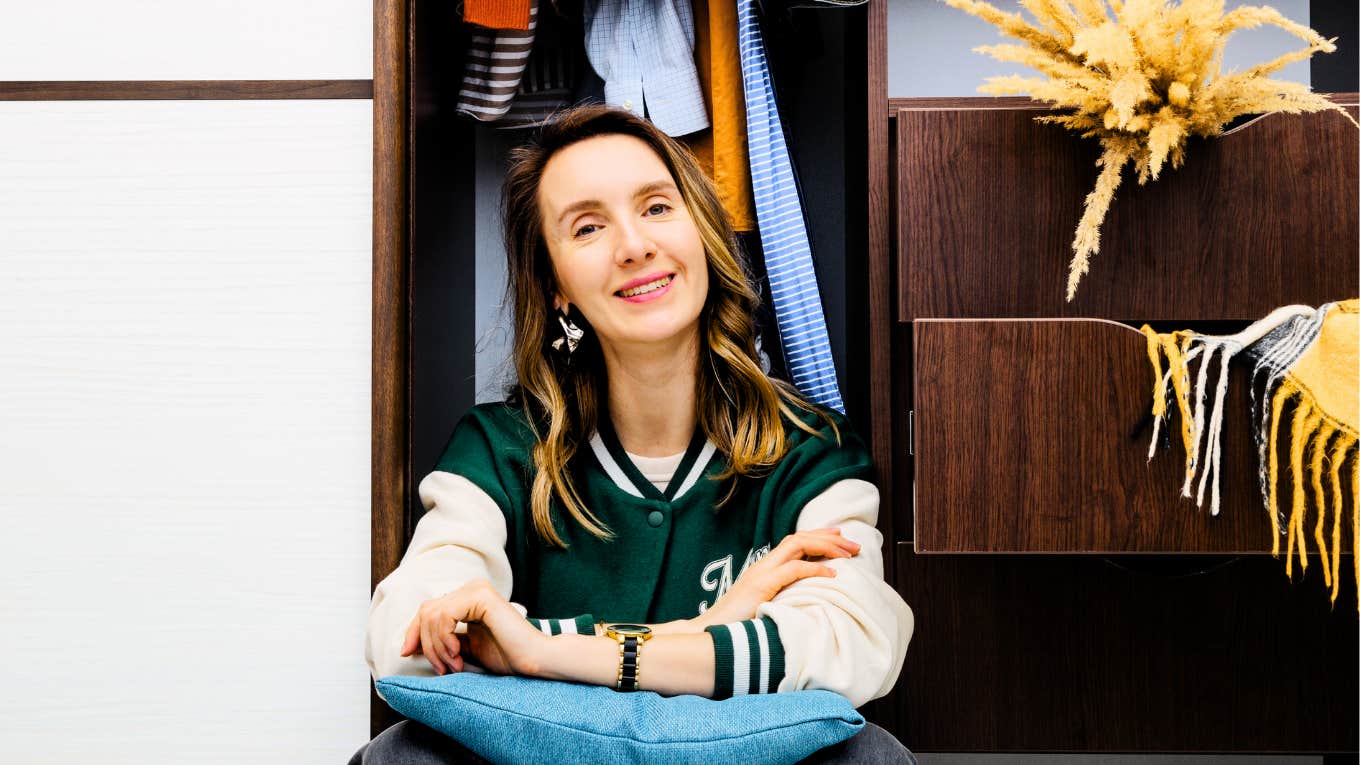 Woman sitting in closet not shopping to retire ten years early.