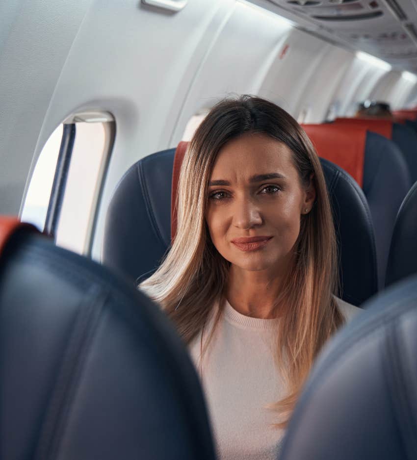 Stressed woman in window seat of plane needs to pee