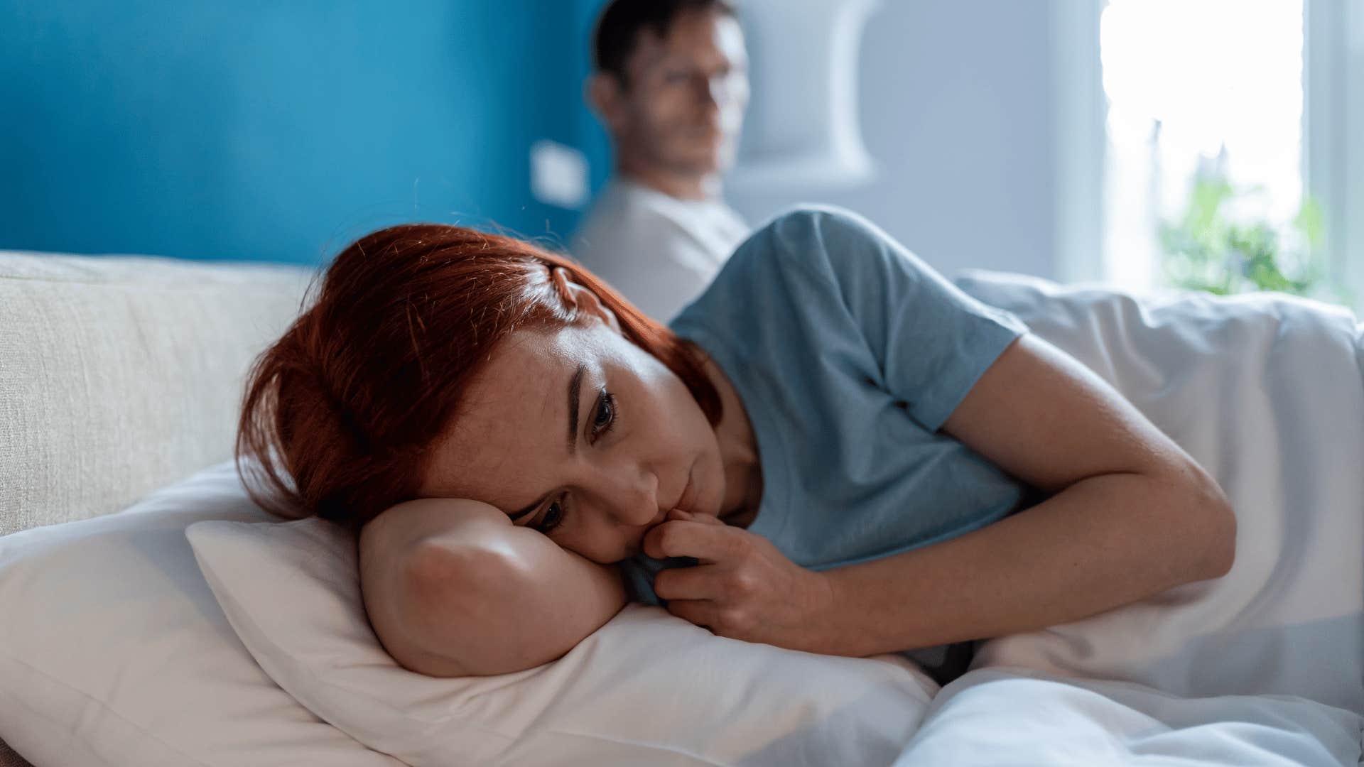 woman contemplating on bed while man watches