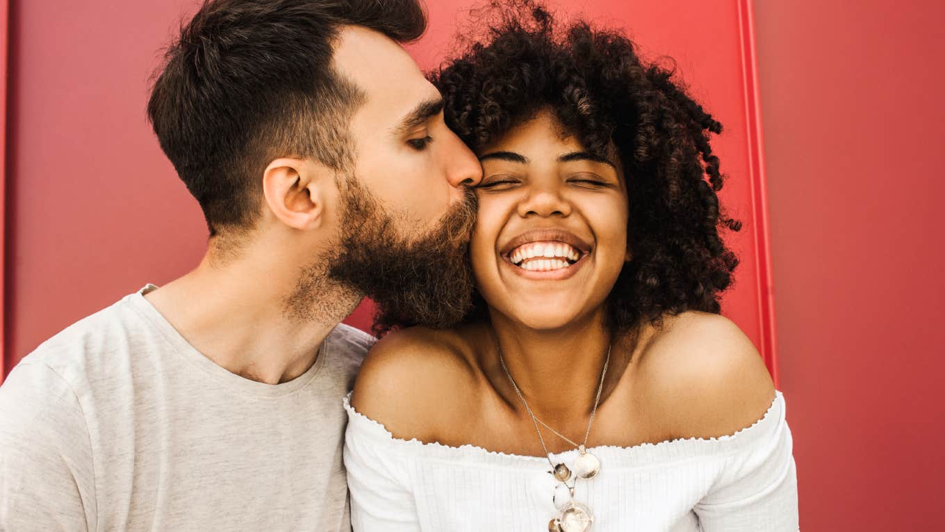 Man kissing woman on cheek, signs he wants to be with you long-term.