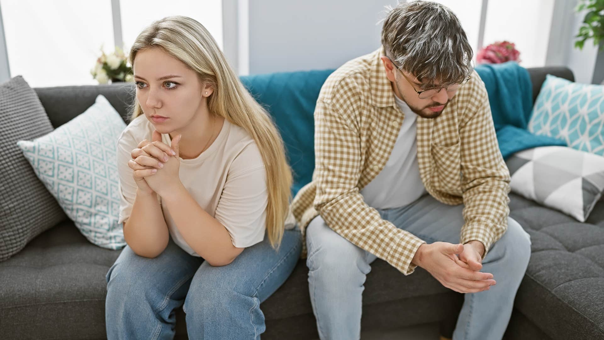 Couple looking upset sitting on the couch.