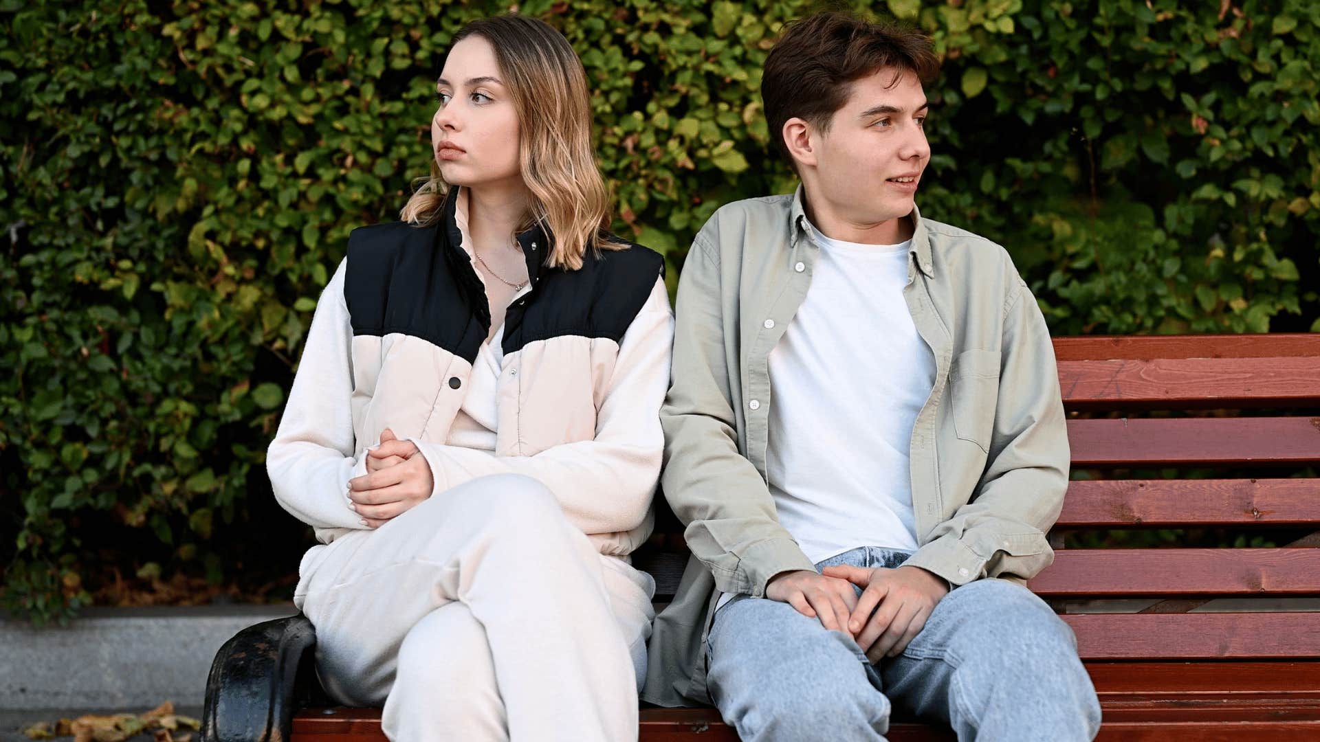 man and woman sitting on bench ignoring each other