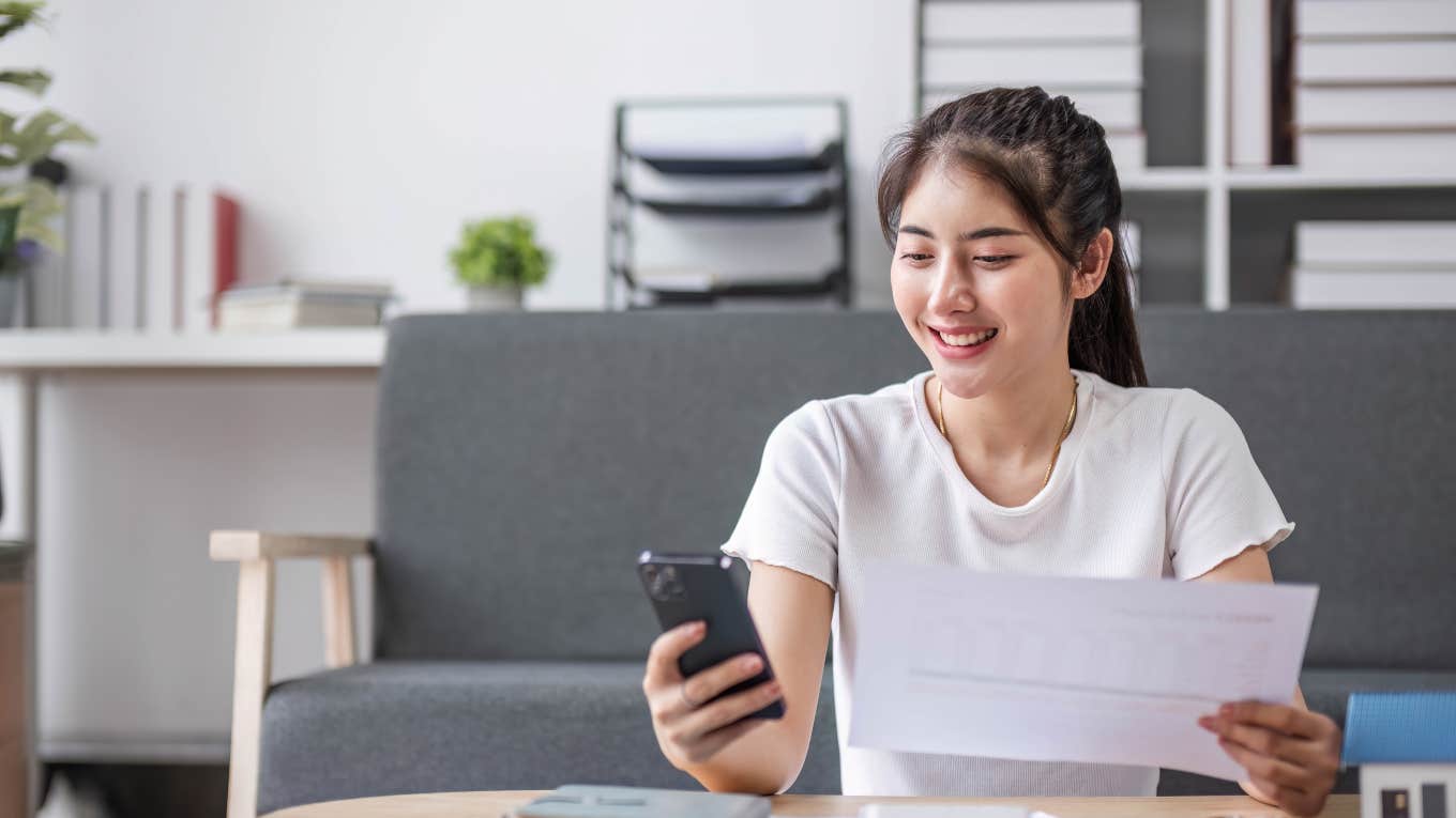 young woman calculating bill totals with paper and phone