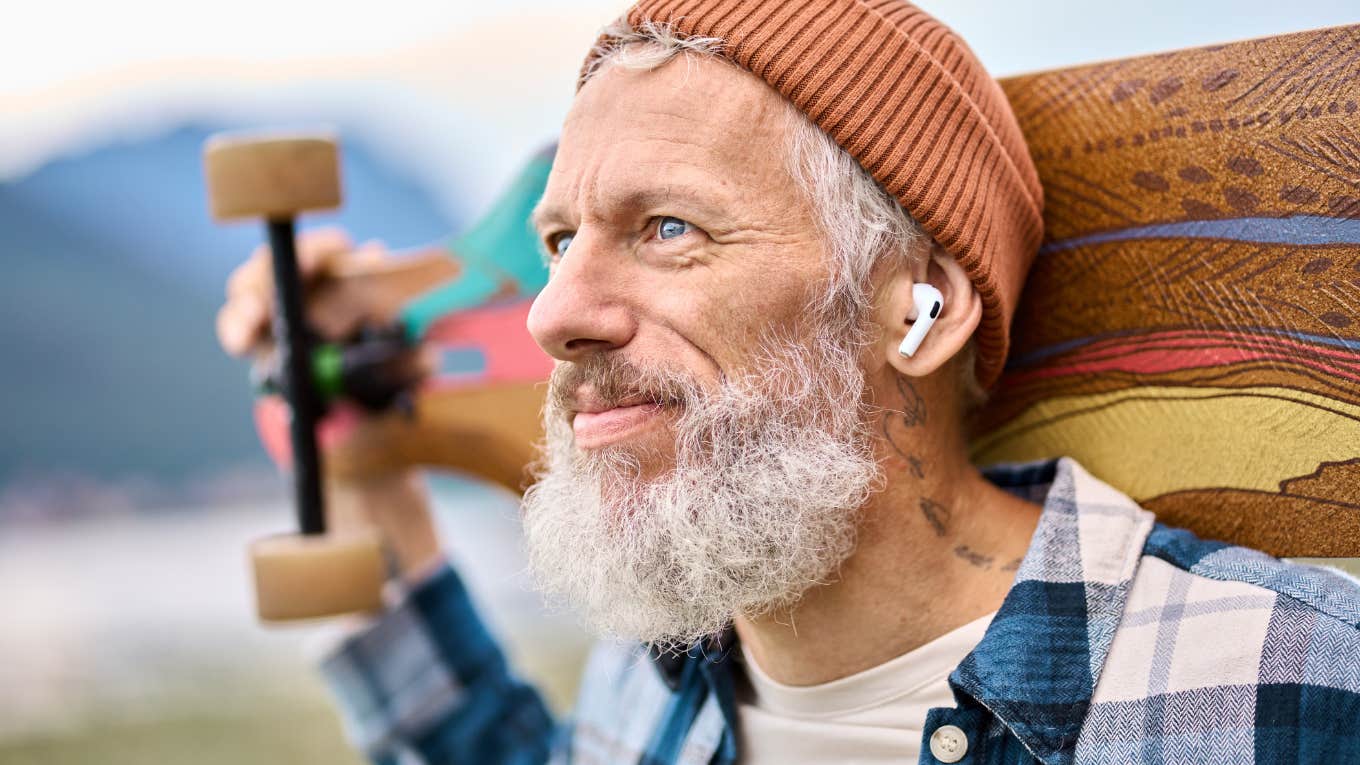 Boomer man smiling and holding a skateboard