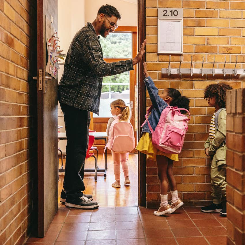 Male teacher greeting students at the door