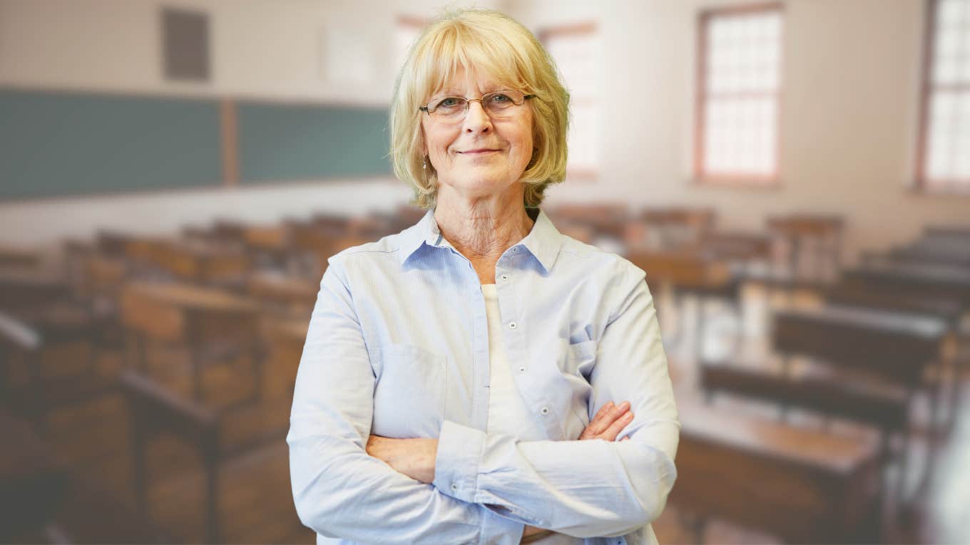 Veteran high school teacher looking smug in front of a classroom. 