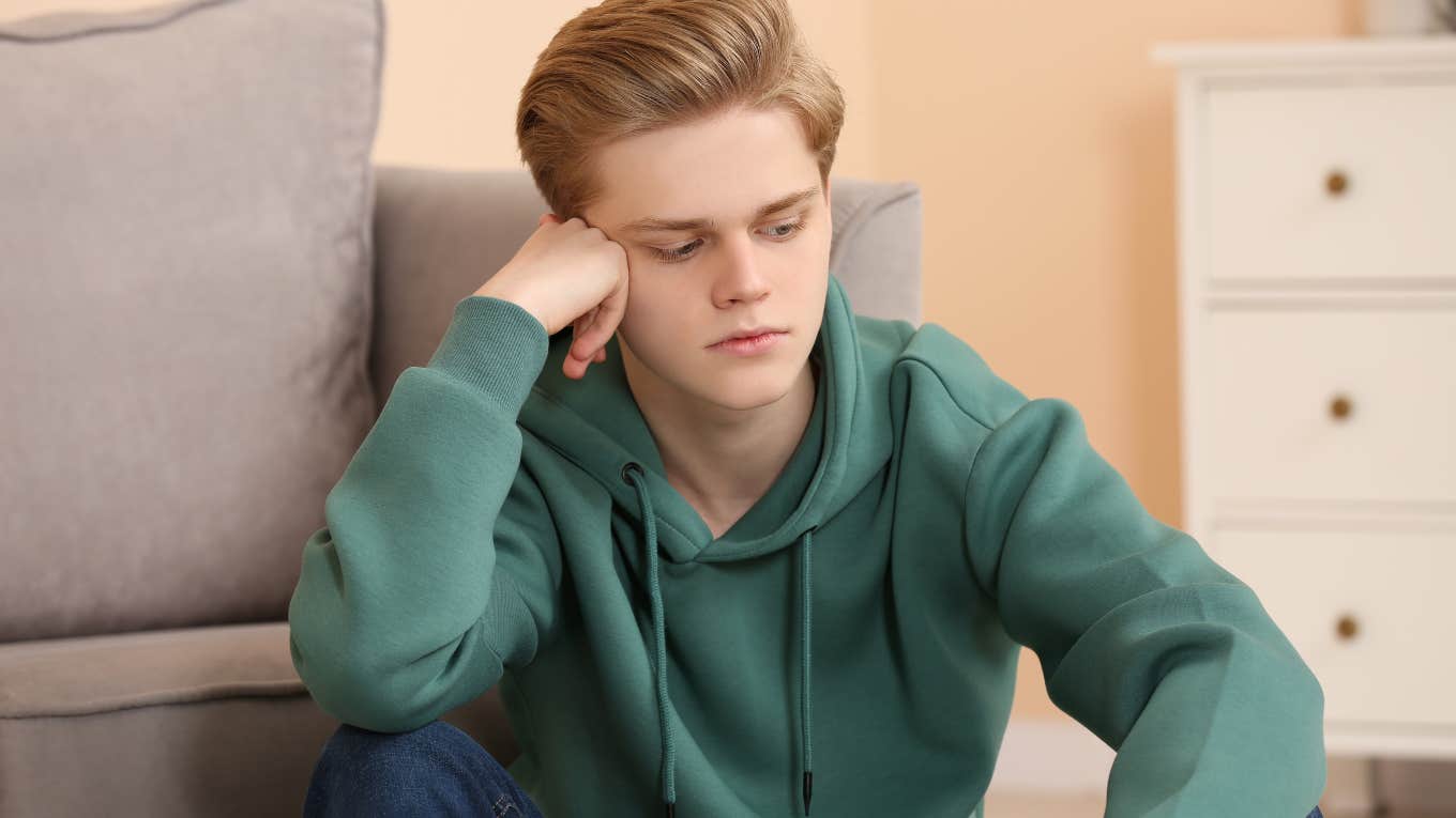 upset teen boy sitting on the ground