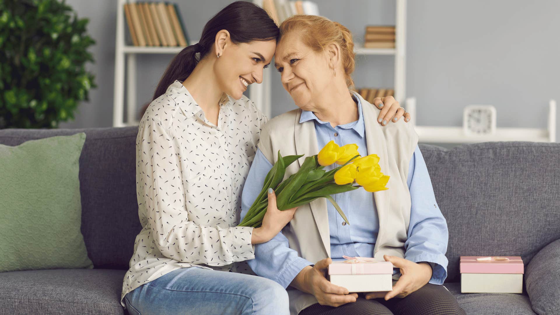 woman giving older woman gifts and hugging her 