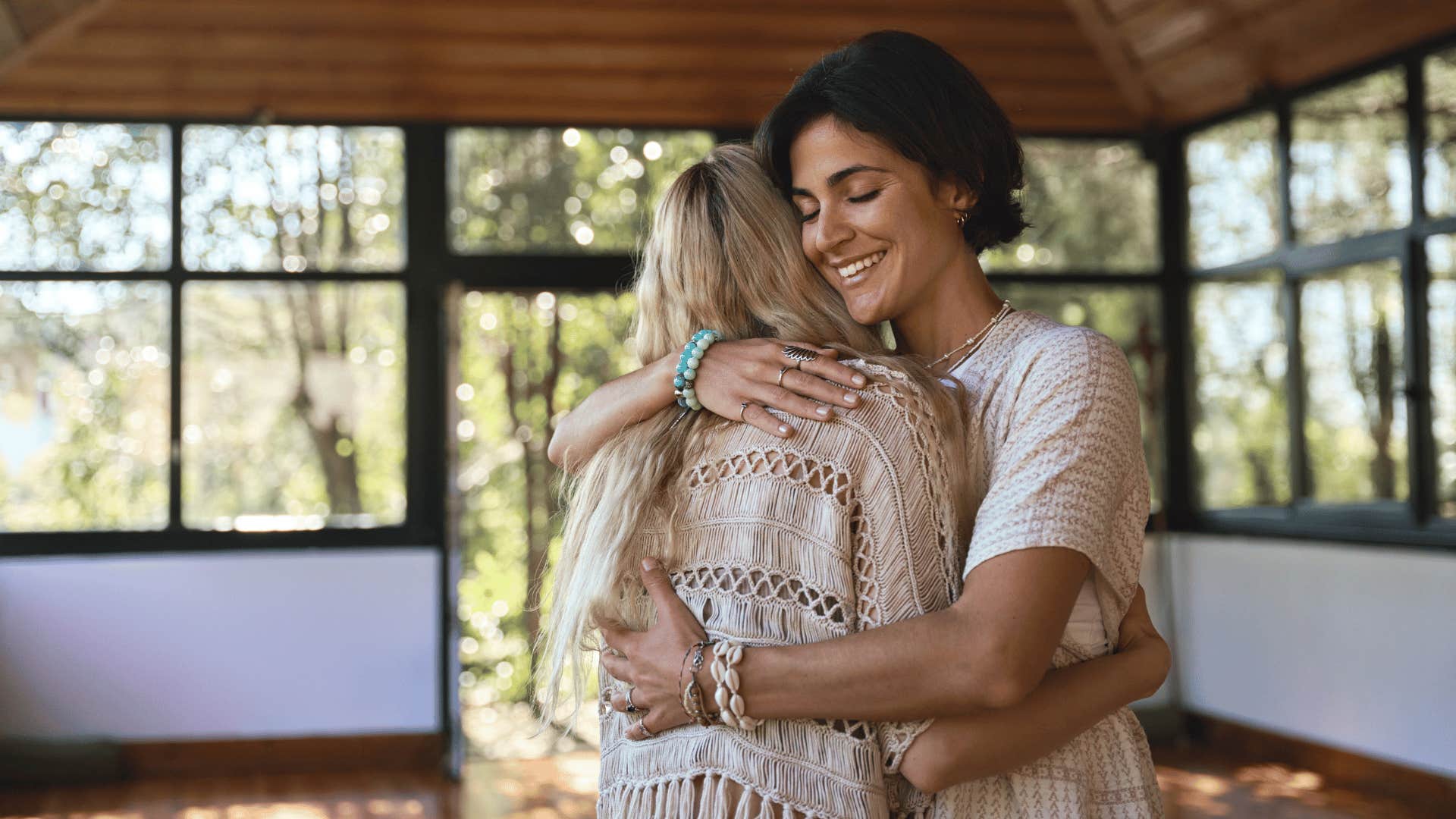 woman hugging other woman while smiling 