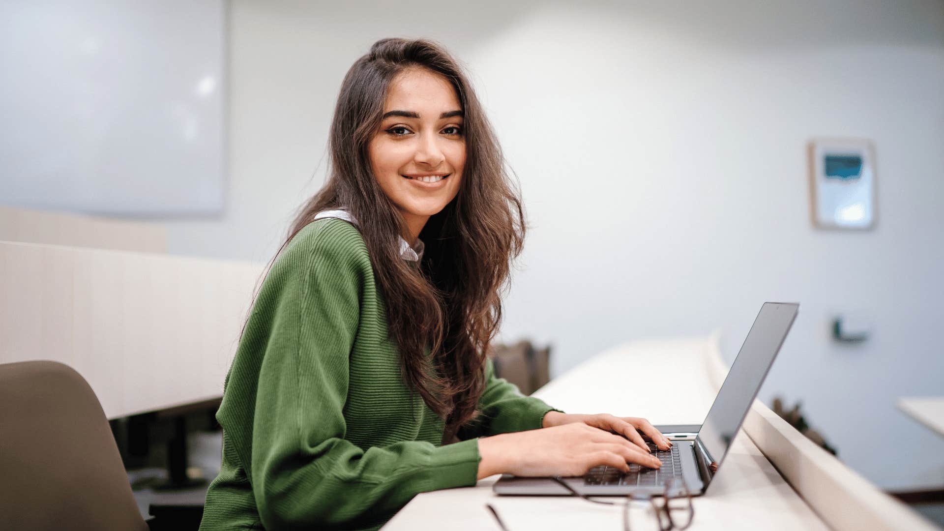 young woman on laptop at school without encyclopedias in the library