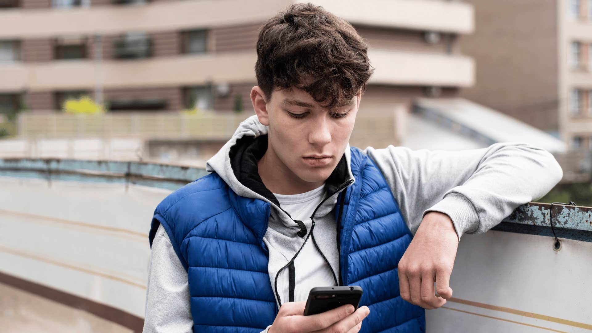 teen boy looking at phone at school with no payphones