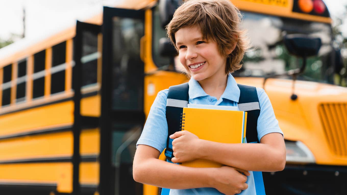 boy in front of yellow school bus