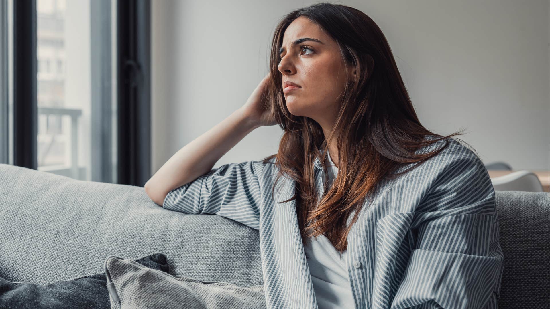 Woman looking lonely and sad on her couch.