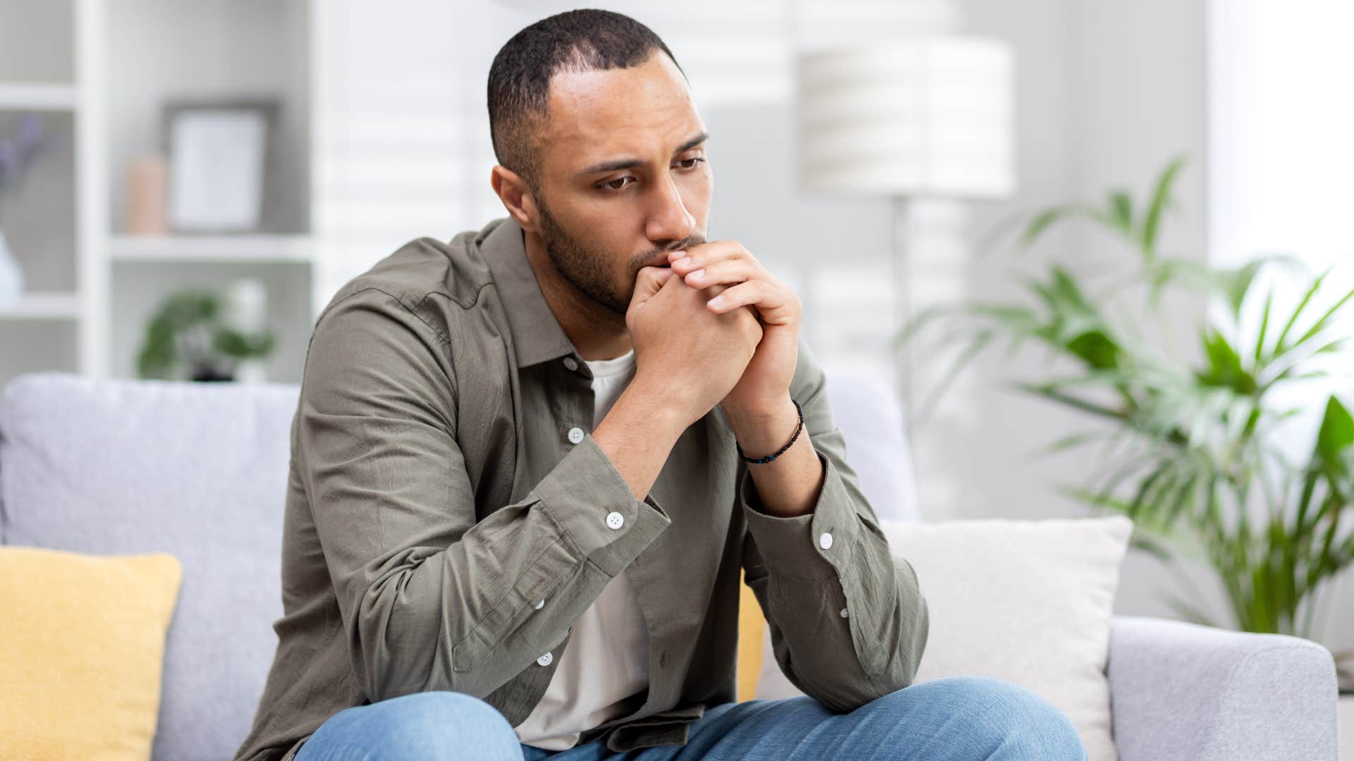 Man looking upset sitting alone at home. 