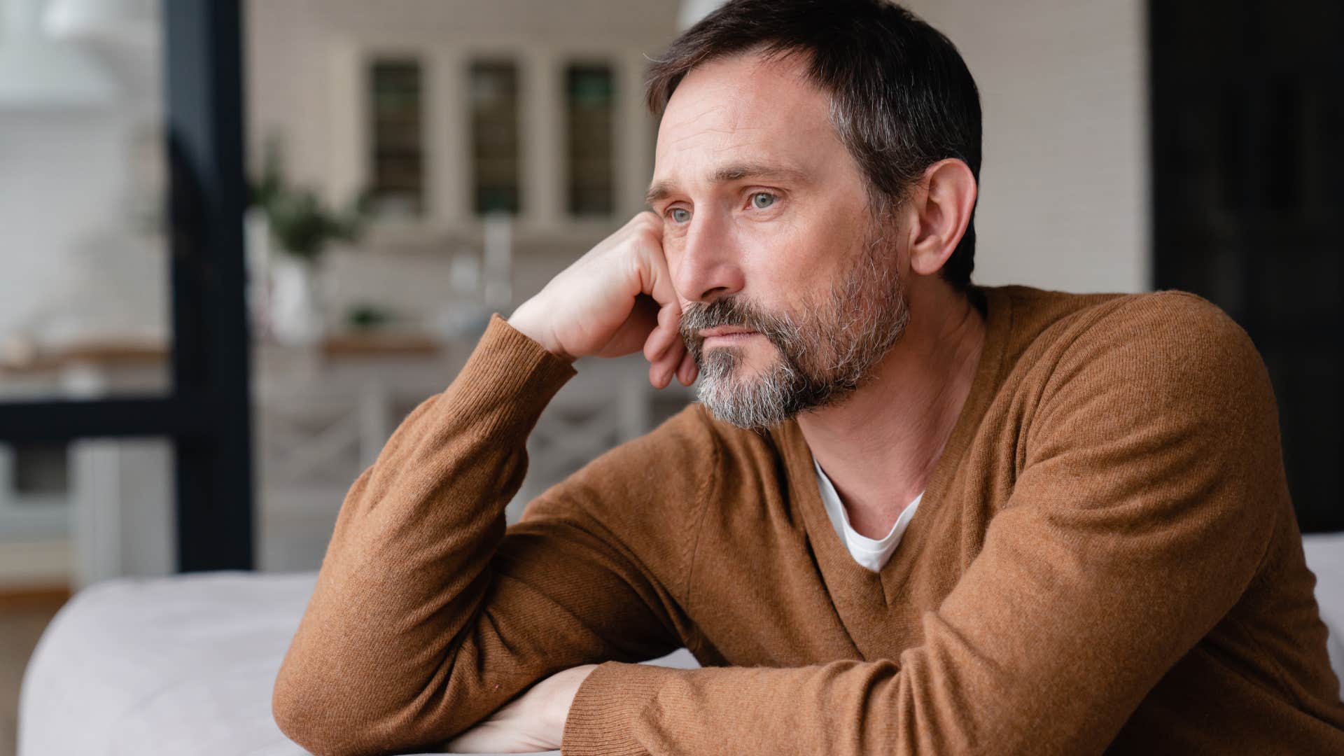 Man looking upset looking out a window. 