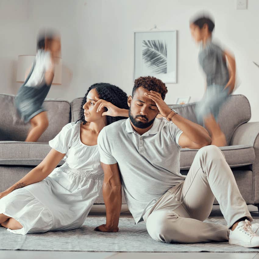 tired parents sitting on the floor while kids play