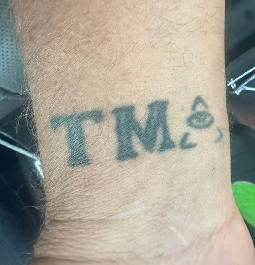 older man's wrist with TMI tattoo