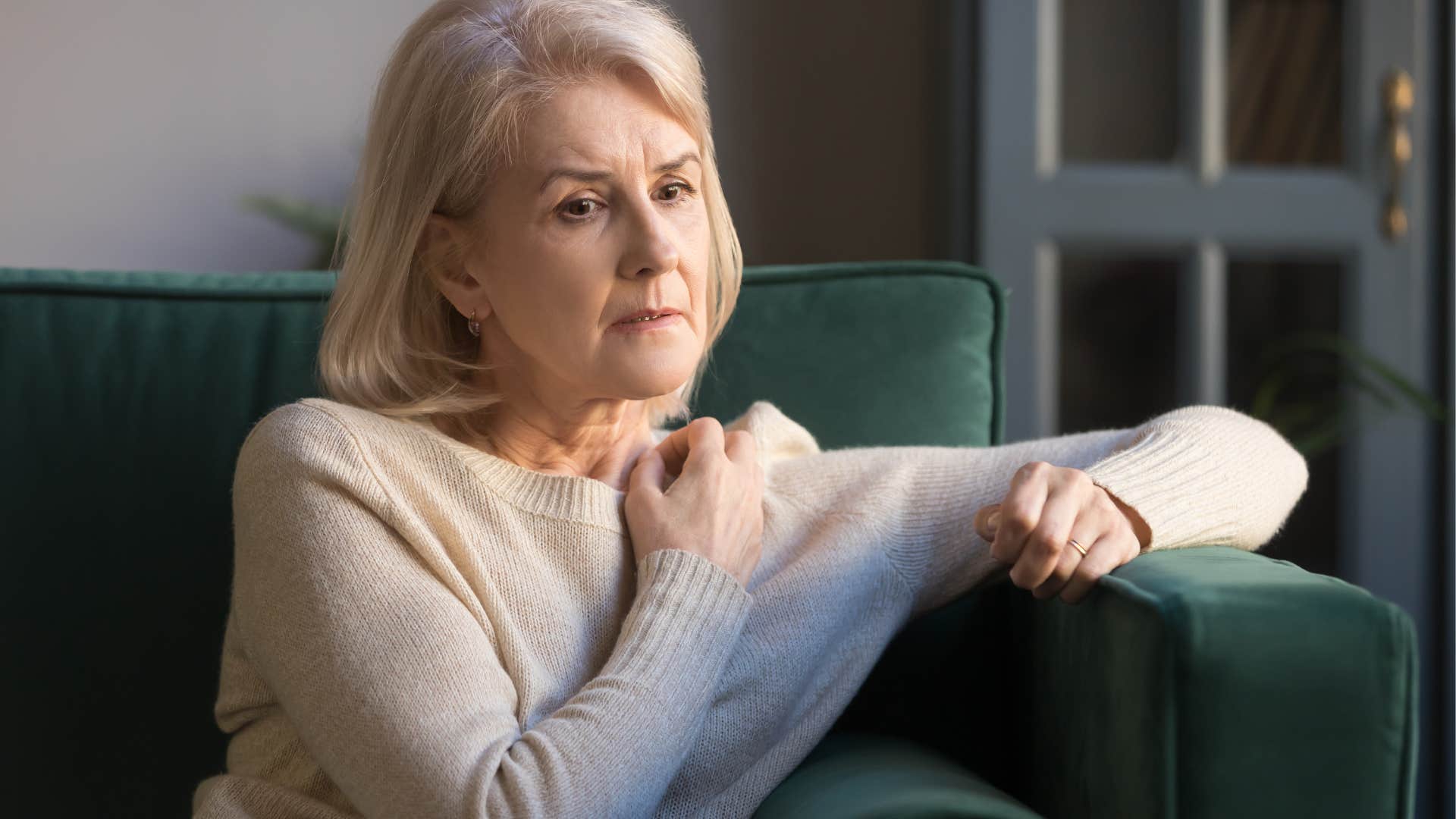 Older woman looking sad on her couch.