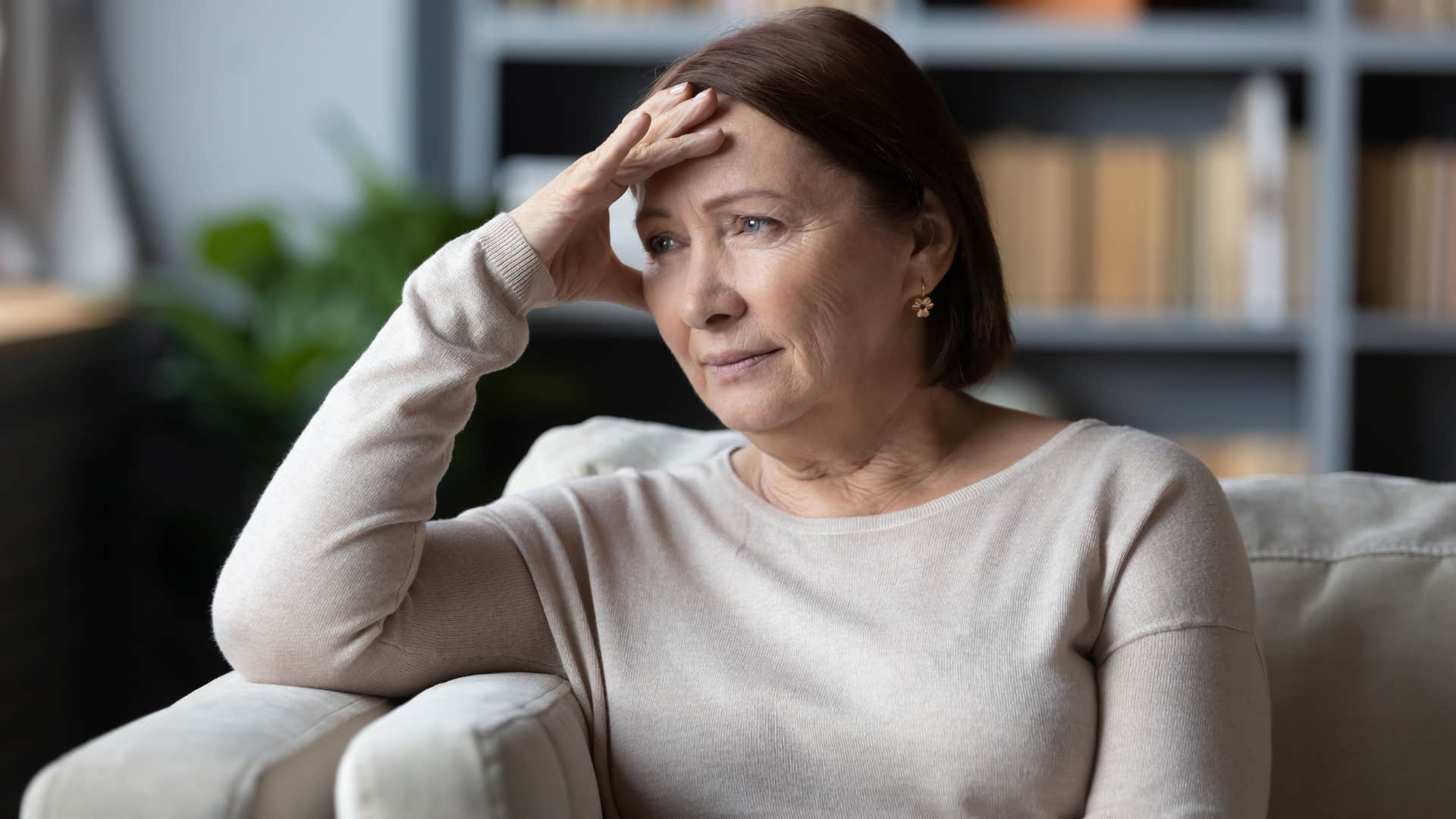 Older woman looking annoyed on her couch. 