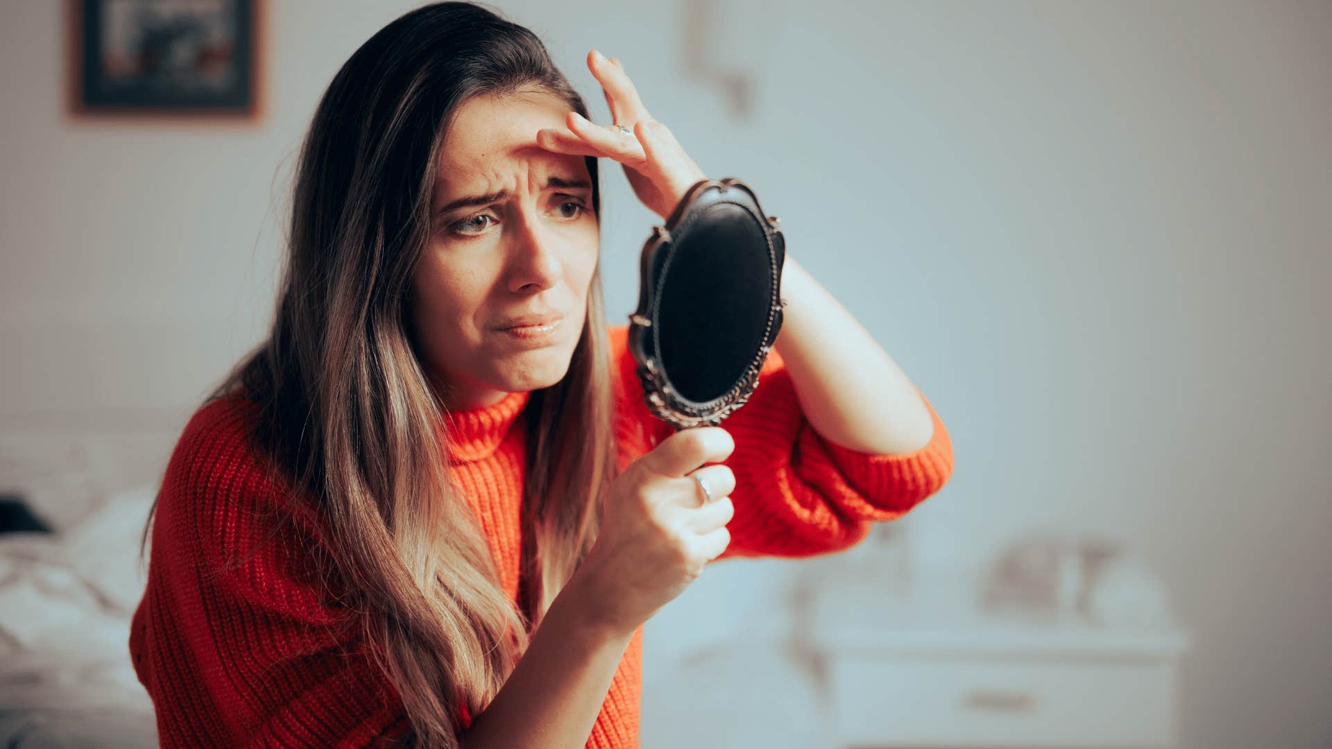 woman being self-conscious and looking in mirror