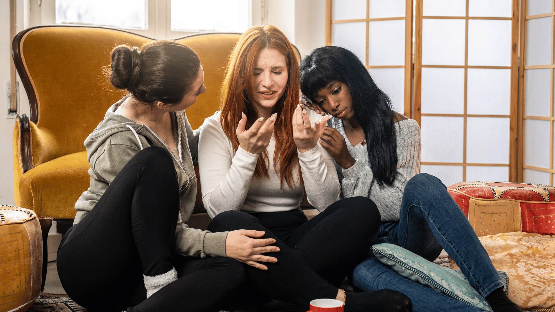 friends comforting other friend while they all sit on floor