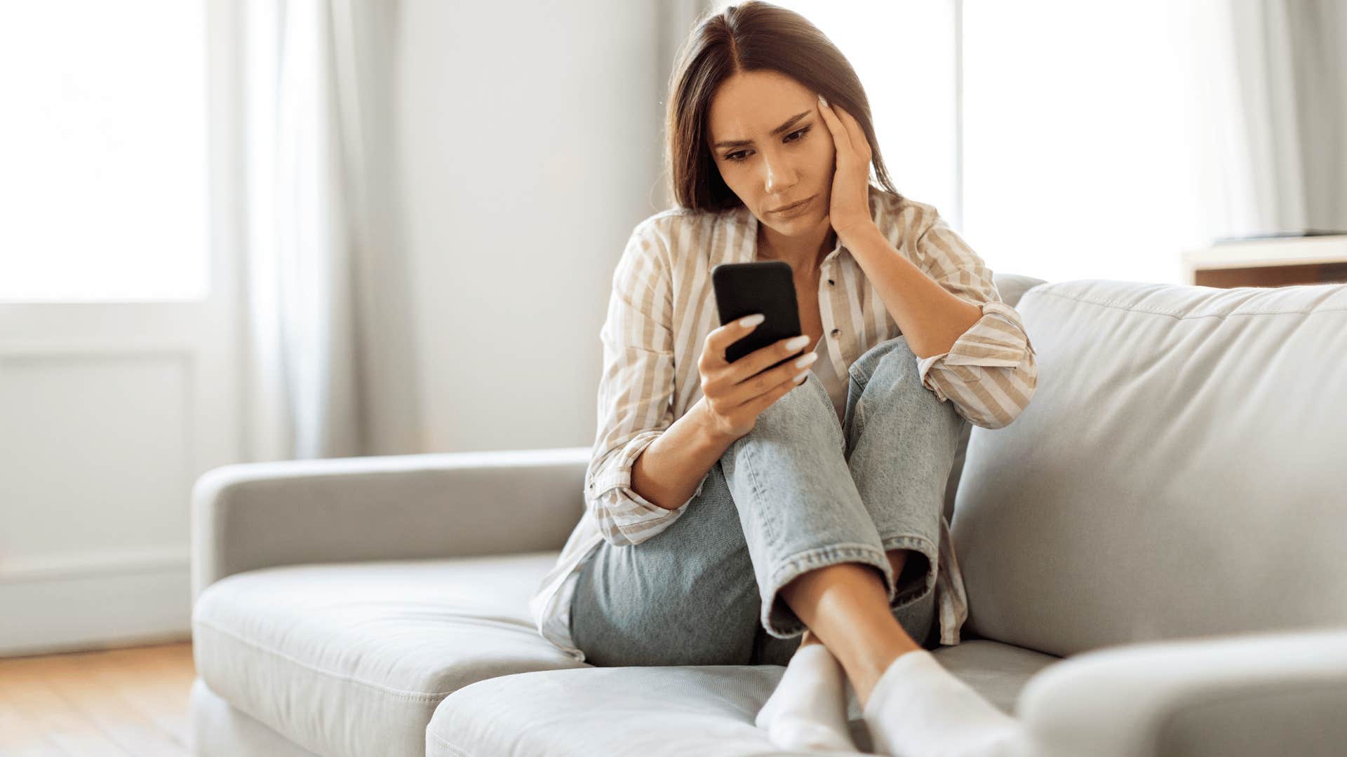 woman checking phone while sitting on couch