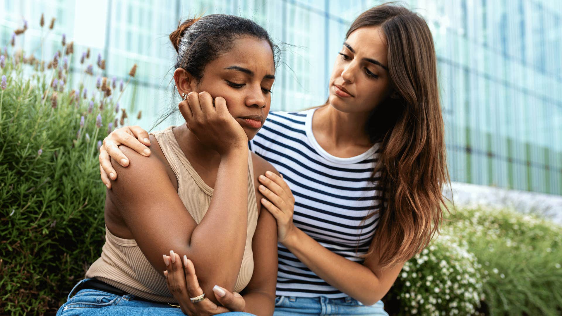 woman comforting friend while sitting on bench