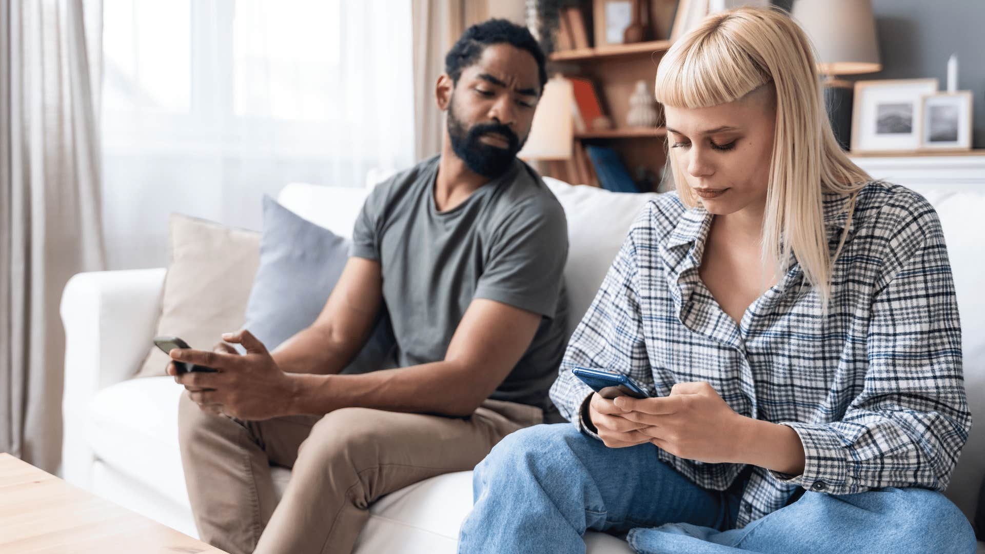 man looking at partners phone while they sit on couch