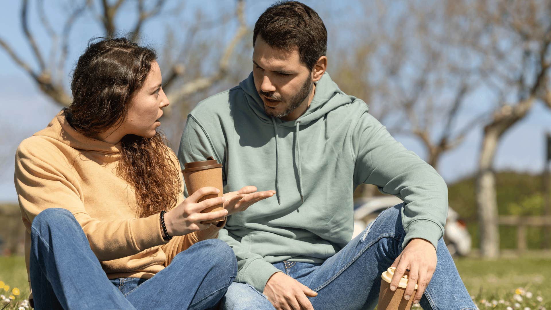 man and woman arguing while sitting on grass