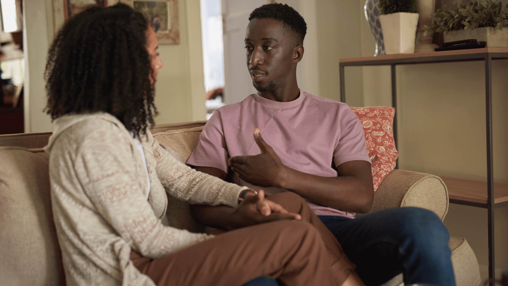 man and woman talking on couch