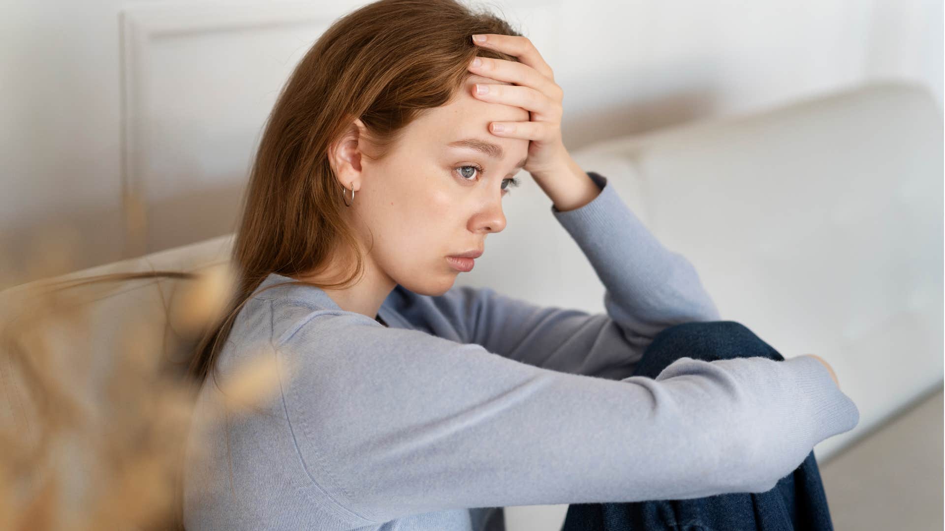 Moody woman looking upset sitting on a couch.