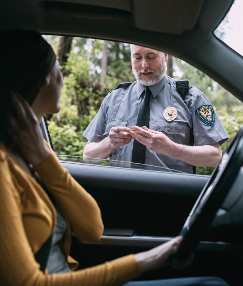 woman handing over insurance during traffic stop with police