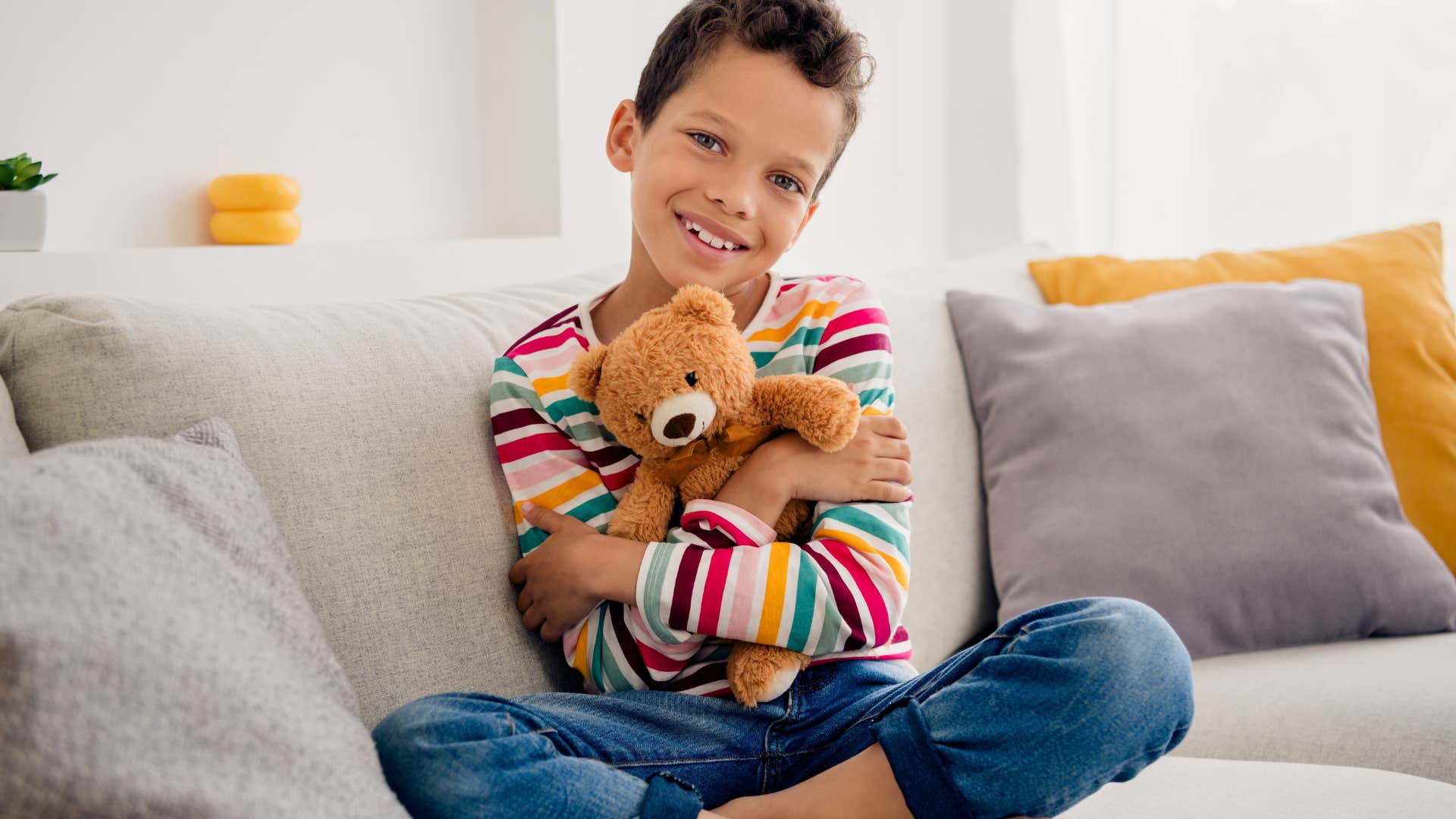 Little boy smiling and hugging his stuffed animal. 