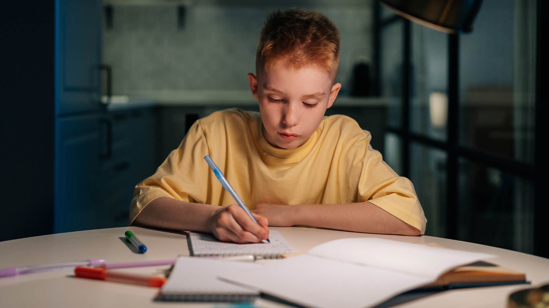 Young boy studying intently at his desk.