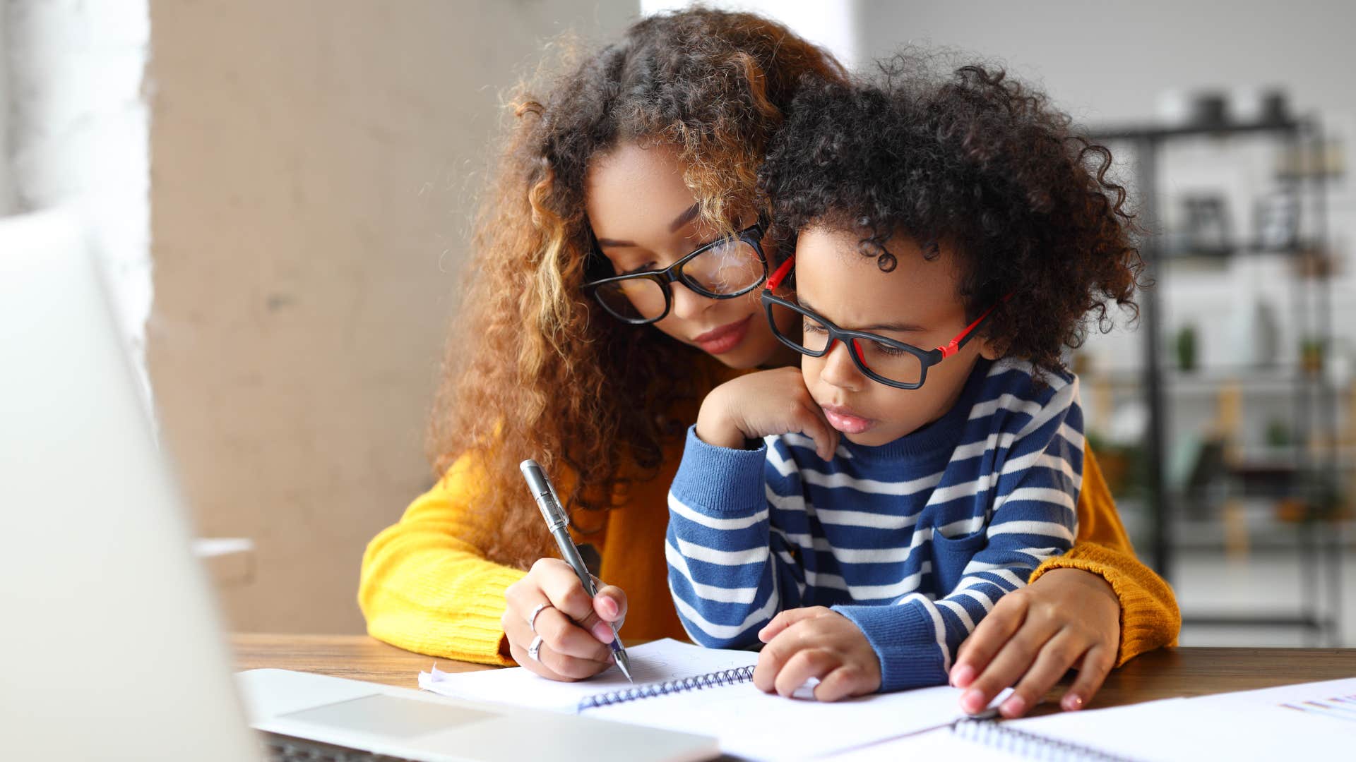 Mom helping her young son with homework at a table. 