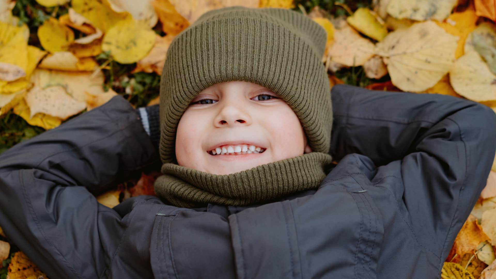 Young boy smiling and laying in the grass. 