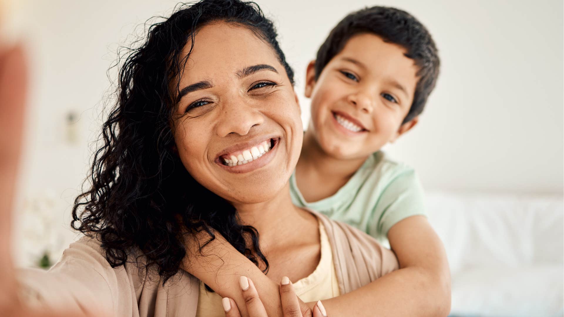 Mom taking a picture smiling with her young son. 